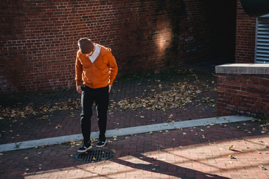 Faceless man standing on street near at road drain
